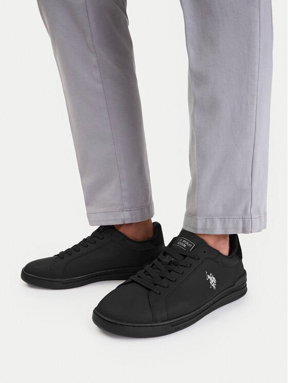 Model prezentujący buty na stopach, nogawki spodni widoczne do kostek.
