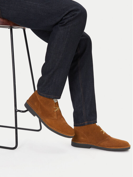 Model siedz?cy, prezentuj?cy buty na stopach, uj?cie od do?u.