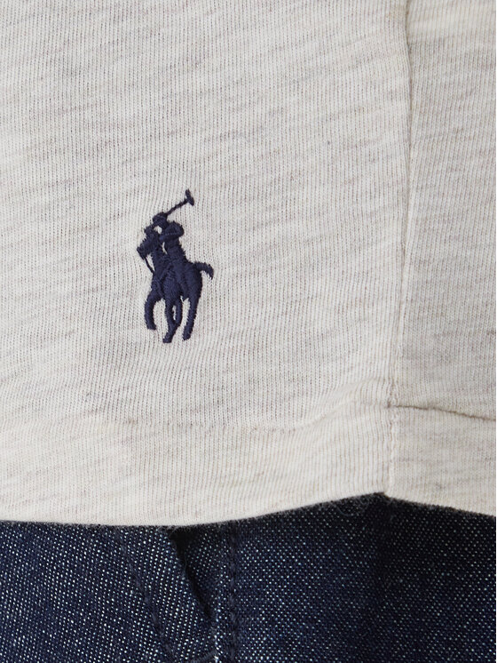 Zbliżenie na dolną część koszulki z logo i fragment spodni.
