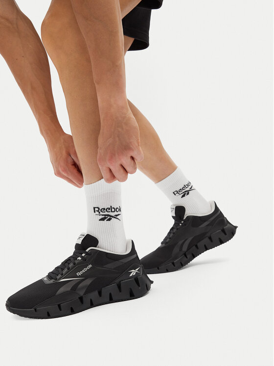 Model zapinający buty, widok na obie stopy w obuwiu.