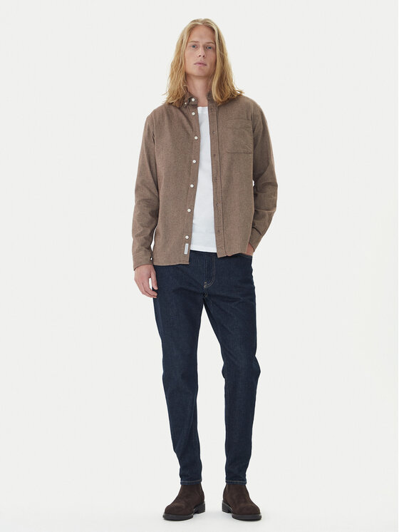 Model w rozpiętej koszuli i jeansach, widoczna cała sylwetka.