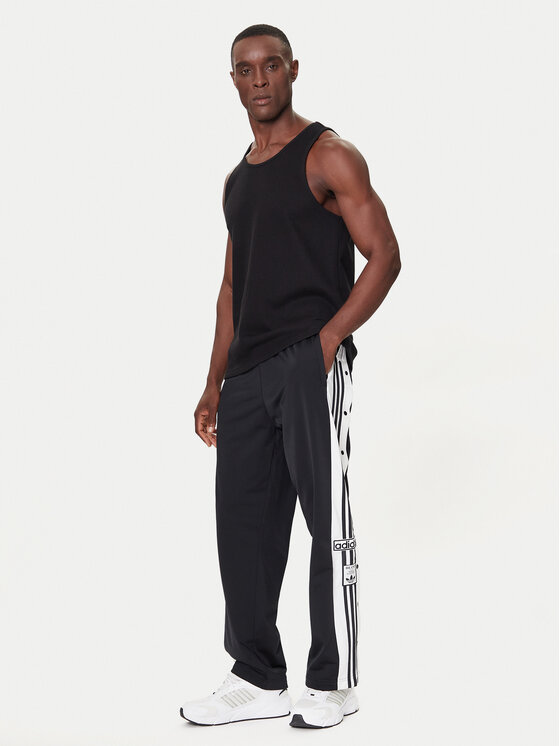 Model w spodniach sportowych i koszulce, ujęcie sylwetki z przodu.