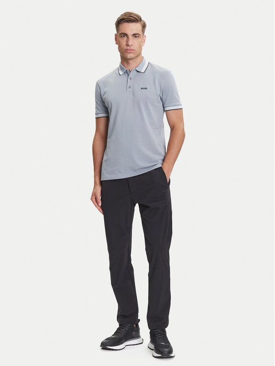 Model w koszulce polo i spodniach, ujęcie całej sylwetki.