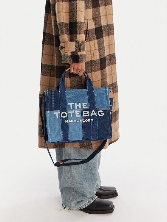 Modelka prezentująca torebkę shopper trzymaną w dłoni przy udzie.