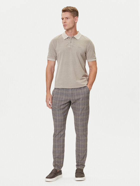 Model w koszulce polo i spodniach, ujęcie całej sylwetki.