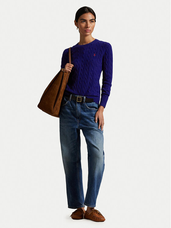 Modelka w swetrze i jeansach, trzyma torbę na ramieniu.
