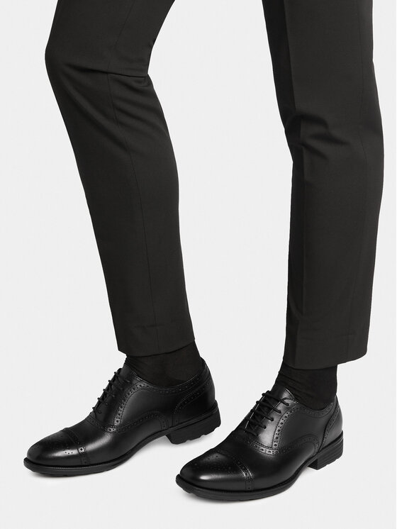 Model w spodniach prezentujący parę eleganckich butów.