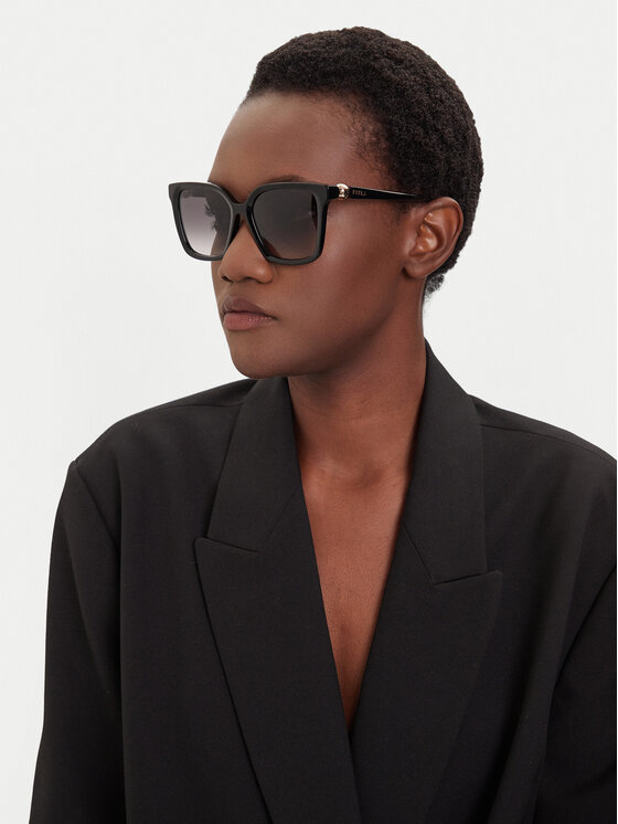 Modelka w marynarce prezentująca okulary przeciwsłoneczne, ujęcie górnej części sylwetki.