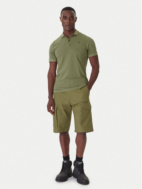 Model w koszulce polo i szortach, pełna sylwetka od góry do dołu.