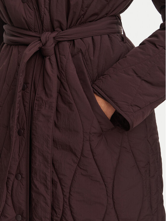 Zbliżenie środkowej części płaszcza z paskiem, dłoń modelki w kieszeni.