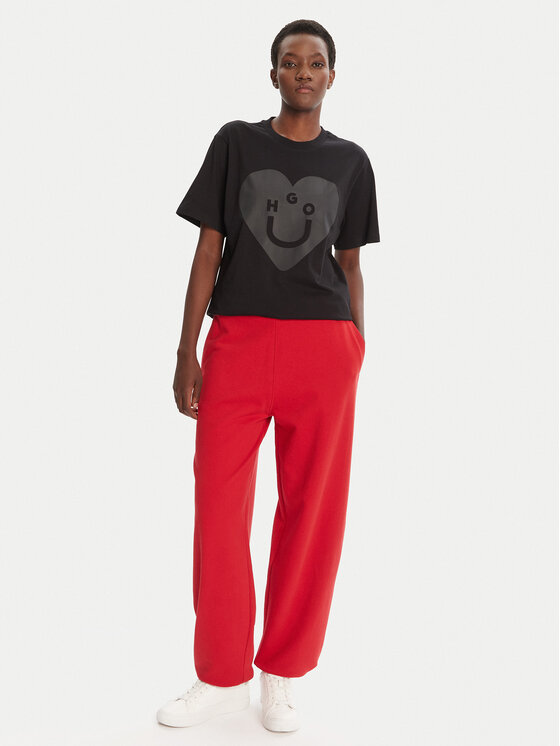 Modelka w pełnej sylwetce, prezentująca T-shirt i spodnie, dłonie w kieszeniach.