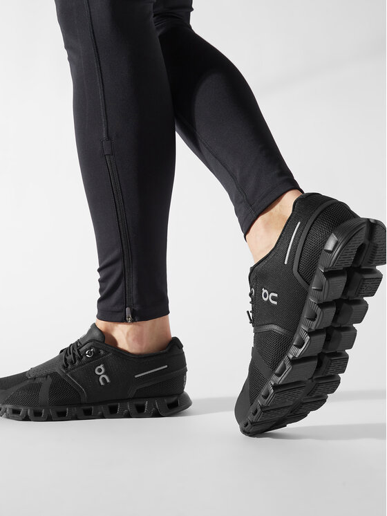 Model w legginsach prezentujący buty sportowe na stopach, ujęcie z boku.