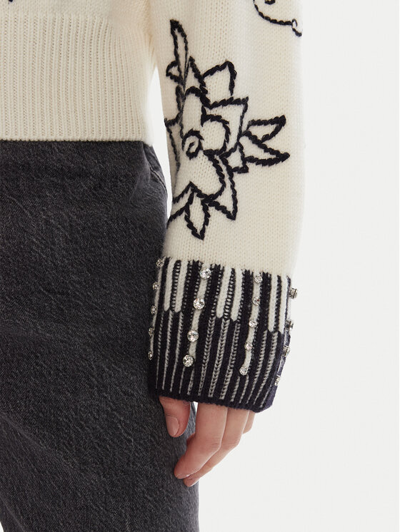 Sweter na modelce, zbliżenie na dół rękawa i fragment spodni.