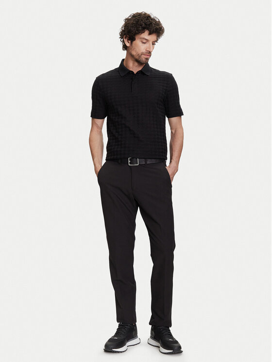 Model w koszulce polo i długich spodniach, ujęcie całej sylwetki.