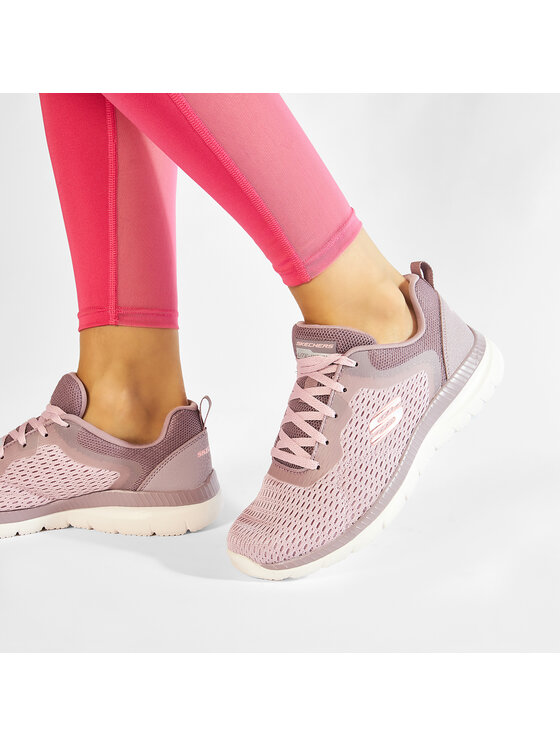 Modelka w legginsach prezentuje buty sportowe na stopach, uj?cie z boku.